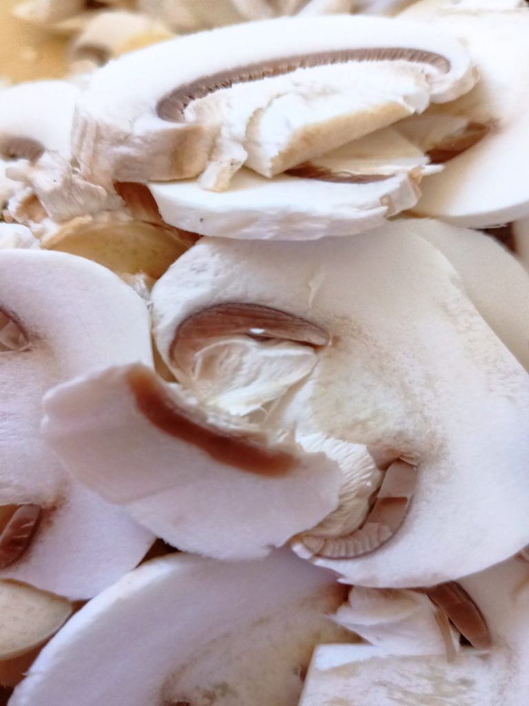 Fresh sliced mushrooms on a cutting board prepared for baked pork loin with mushrooms and soft white sauce.