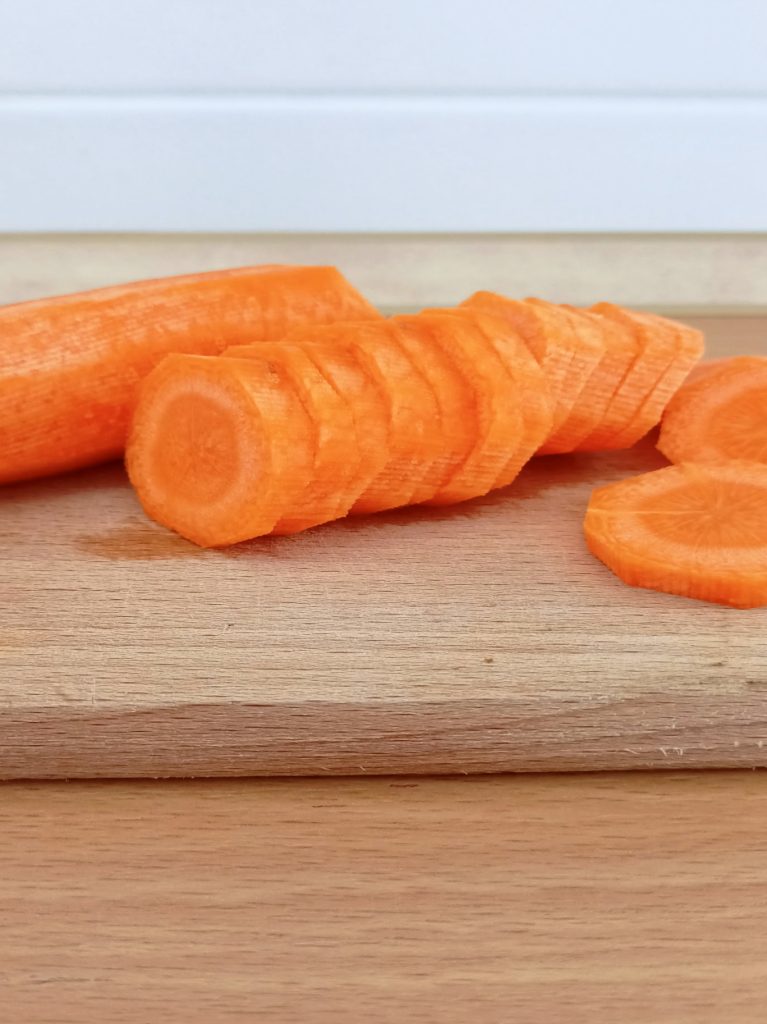 Fresh chopped carrots on a cutting board prepared for one-basket air fryer chicken with vegetables.