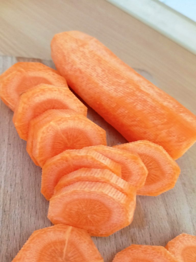 Fresh chopped carrots on a cutting board prepared for quick chicken and vegetable skillet stew.