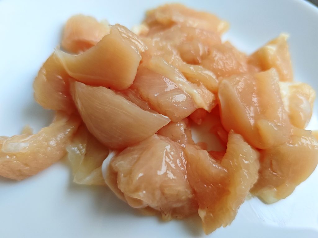 Cooked chicken cut into bite-sized pieces on a wooden board