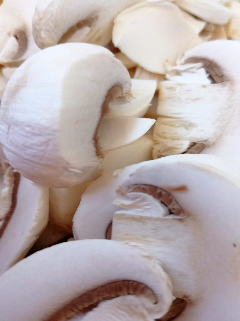 Fresh sliced mushrooms on a cutting board prepared for easy gnocchi with mushrooms and Brussels sprouts.