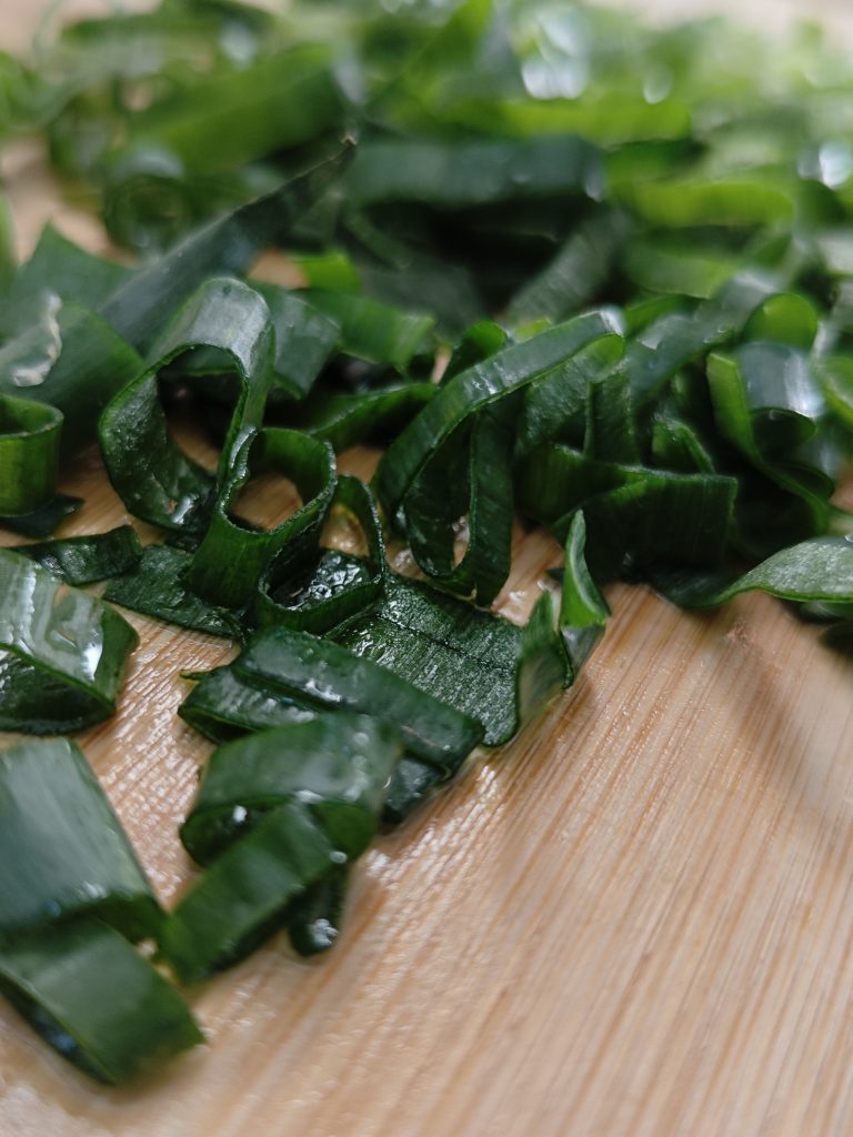 Fresh sliced green onions on a cutting board prepared for easy shrimp stir fry.