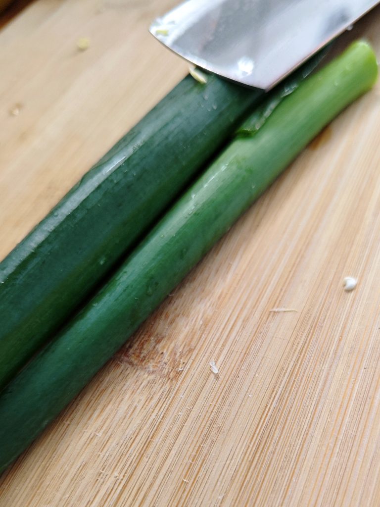 Fresh chopped green onions on a cutting board prepared for easy vegetarian pad thai with tofu and ginger.