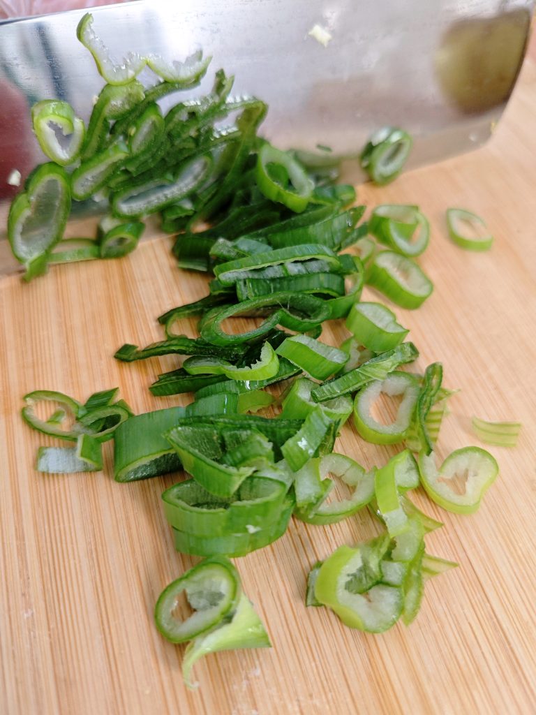 Fresh sliced green onions on a cutting board prepared for quick vegetable noodle stir-fry.