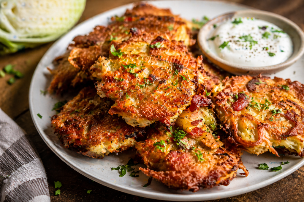 Crispy cabbage and bacon fritters served on a plate with creamy dipping sauce, golden brown and crunchy
