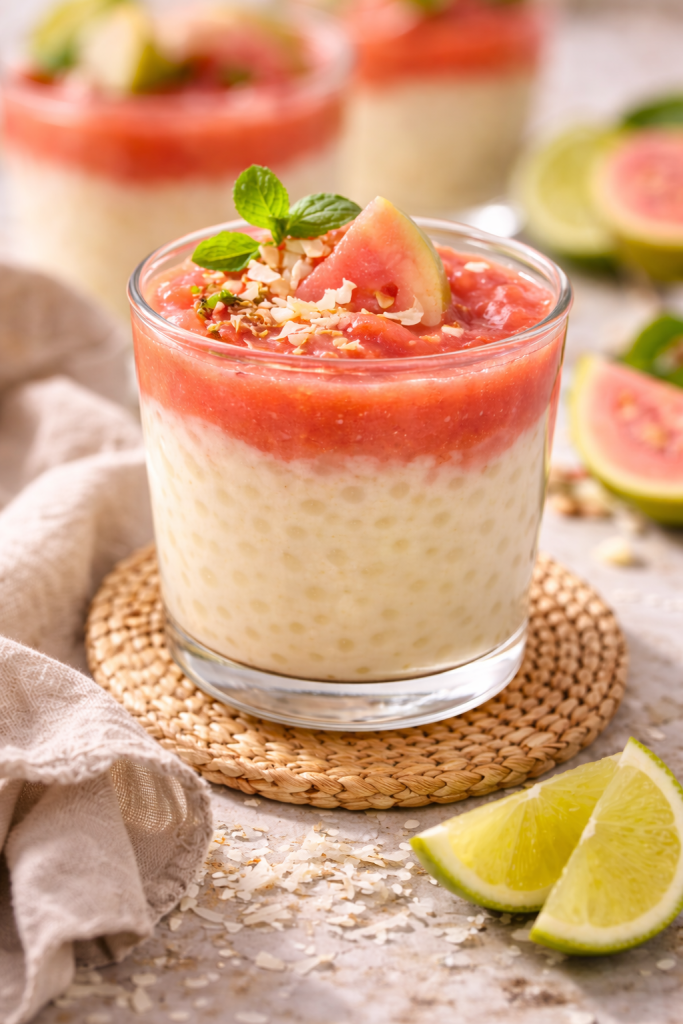 Tapioca pudding with guava puree layered in a glass, topped with mint and coconut flakes
