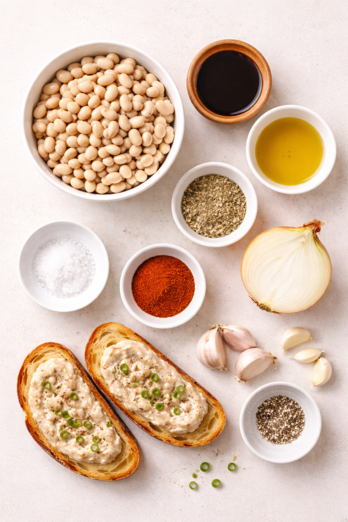 Ingredients for vegan lard made from white beans arranged neatly on a light surface with garlic, onion, spices and oil